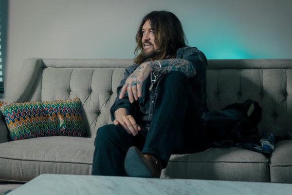 BILLY RAY CYRUS ON COUCH WITH FOOT ON TABLE MattBlake